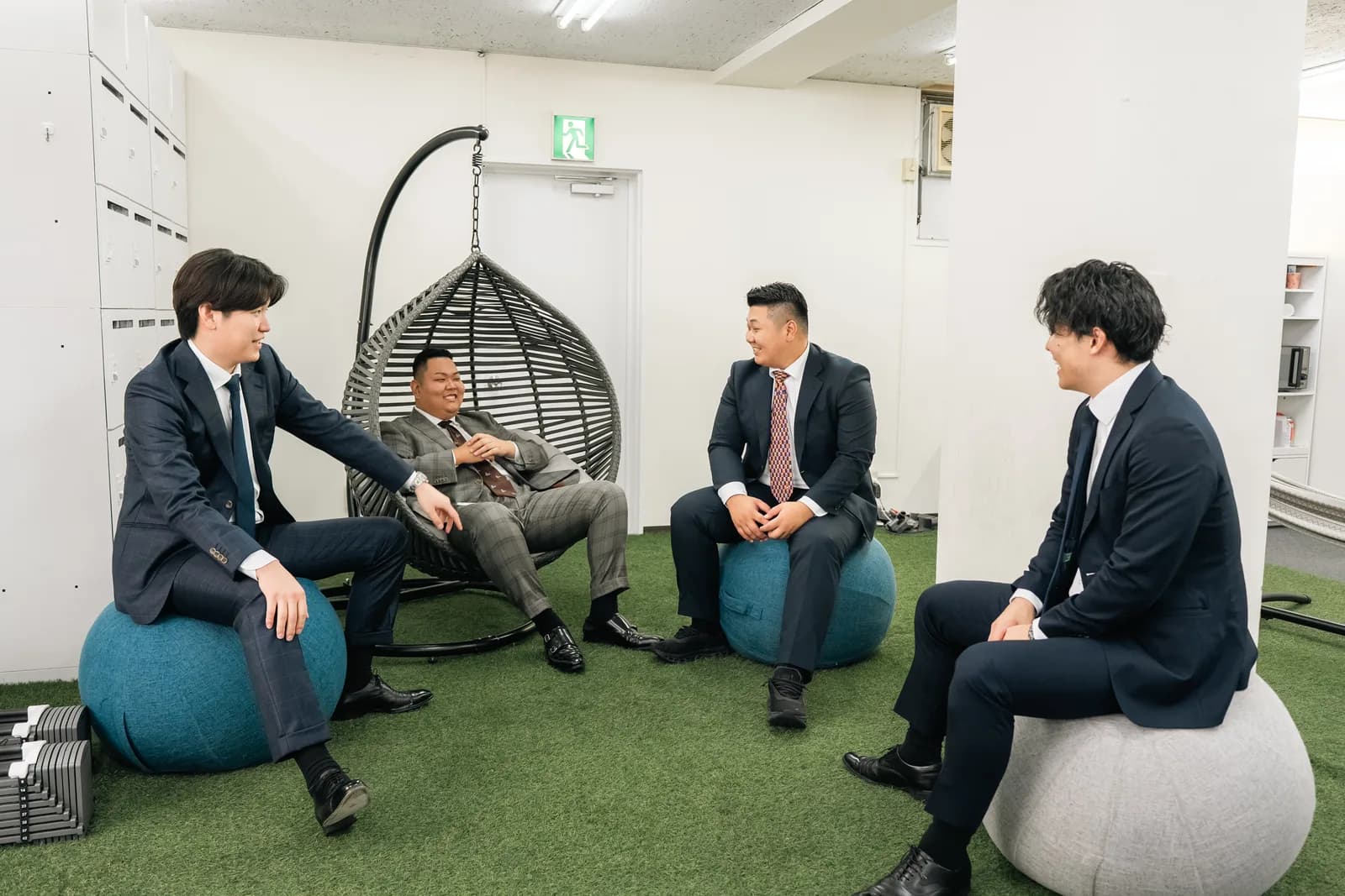 オフィスのラウンジで輪になって話す4人のメンバー